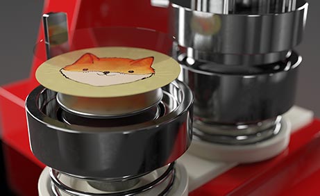 Nahaufnahme der Buttonpresse mit Einzelteilen des zu stanzenden Buttons, Motiv: gezeichneter Fuchs