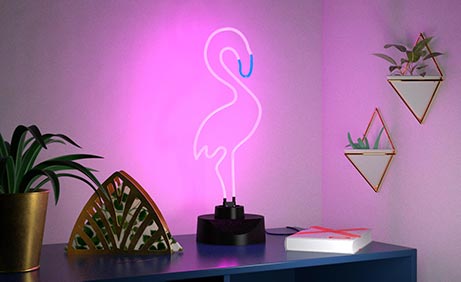 Neon-Lampe in Flamingoform auf dunkelblauem Holzregal